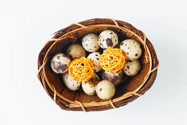 Œufs de caille isolés dans un panier avec des boules décoratives en bois — Photo