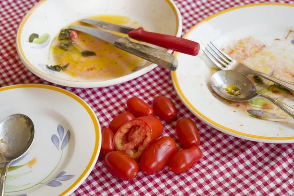 Świeże pomidory na stole z brudnych talerzy — Zdjęcie stockowe