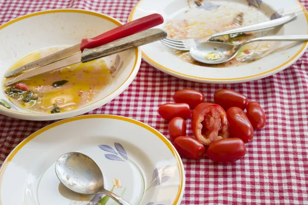 Świeże pomidory na stole z brudnych talerzy — Zdjęcie stockowe