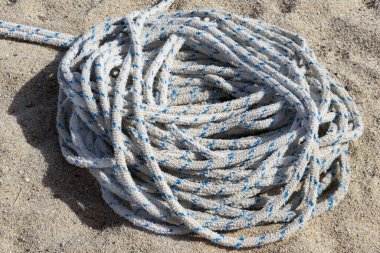 Sıcak, desenli sarı kuma sarılmış, kalın, beyaz ve mavi benekli deniz ipine yakın çekim. Sığ alan derinliği, parlak açık hava yaz seyahati veya tekne gezisi konsepti