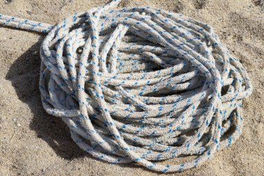 Sıcak, desenli sarı kuma sarılmış, kalın, beyaz ve mavi benekli deniz ipine yakın çekim. Sığ alan derinliği, parlak açık hava yaz seyahati veya tekne gezisi konsepti