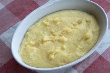 Beyaz bir tabakta rendelenmiş peynirli İtalyan kremalı polenta.