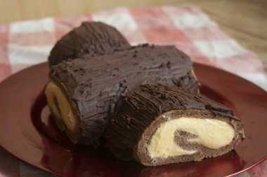 Noel tatili ve kış mevsimi için kırmızı tabakta kremalı zengin çikolatalı Noel pastası.