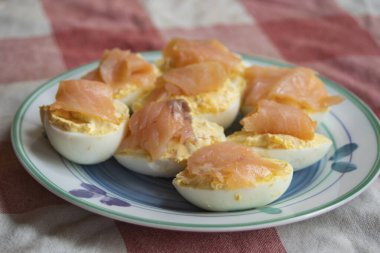 Taze füme somon dilimleriyle kaplı nefis baharatlı yumurtalar sade keto brunch ve protein zengini abur cuburlar için mükemmel damalı masa örtüsü servis edilir.