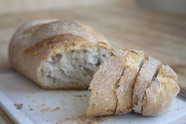 Ev yapımı, kabuklu, altın hamurlu ekmek. Tahta üzerinde dilimler halinde kesilmiş, köy usulü fırın tarzı.
