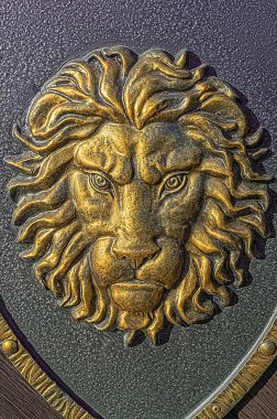 Kapıda metal sarısı boyalı aslan süslemesi.