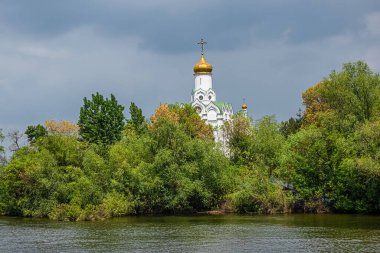 Nehir adasındaki Ortodoks Hıristiyan Kilisesi yemyeşil ağaçların arasında.