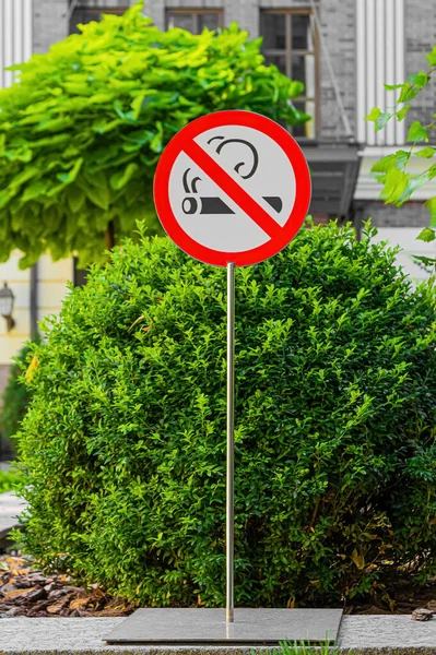 Metal pole with no smoking sign in public place.