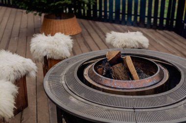 Sıcak bir terasta yanan odunları olan açık hava ateş çukuruna.
