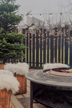 Sıcak bir terasta yanan odunları olan açık hava ateş çukuruna.