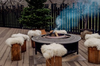 Sıcak bir terasta yanan odunları olan açık hava ateş çukuruna.