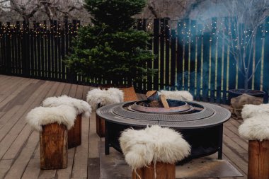 Sıcak bir terasta yanan odunları olan açık hava ateş çukuruna.