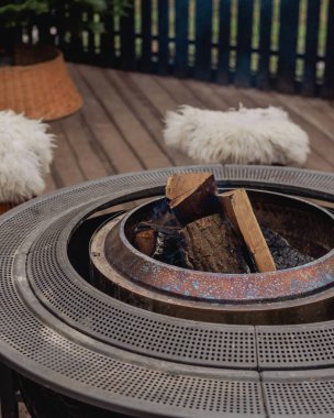 Sıcak bir terasta yanan odunları olan açık hava ateş çukuruna.