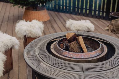 Sıcak bir terasta yanan odunları olan açık hava ateş çukuruna.