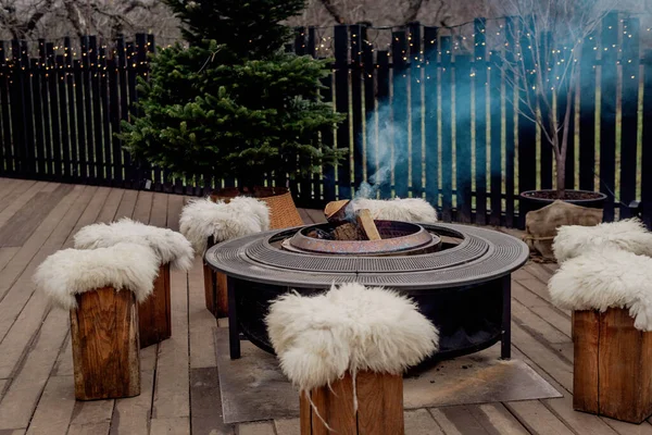 Sıcak bir terasta yanan odunları olan açık hava ateş çukuruna.