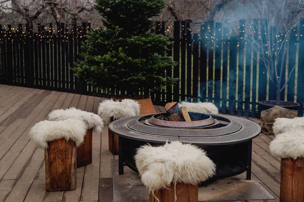 Sıcak bir terasta yanan odunları olan açık hava ateş çukuruna.