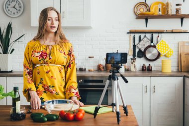 Genç, güzel, hamile kız blogcu akıllı telefon kamerasıyla salata tarifinin videosunu çekiyor. Sağlıklı beslenme kavramı. Tonlama.