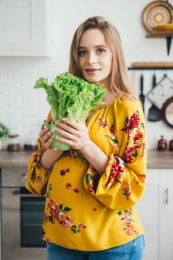 Genç ve güzel hamile kız mutfakta sebze salatası hazırlıyor. Sağlıklı beslenme kavramı. Tonlama.