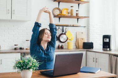 Genç hamile ve serbest çalışan kız karantinada kendini izole etme modunda mutfakta çalışıyor ve yorgunluktan ısınıyor. Tonlama.