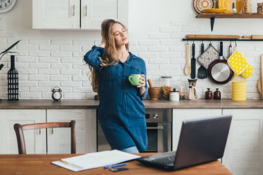 Genç ve güzel hamile bir kız karantinada kendini izole etme modunda çalışıyor ve dinlenmek için kahve molası veriyor. Tonlama.