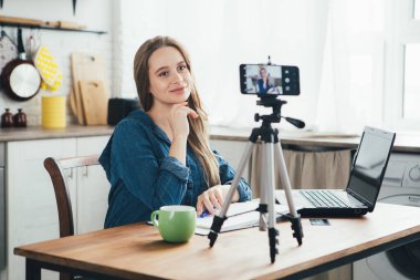 Genç ve güzel hamile bir kız karantinada kendini izole etme modunda çalışıyor ve akıllı telefonuyla video kaydediyor. Tonlama.