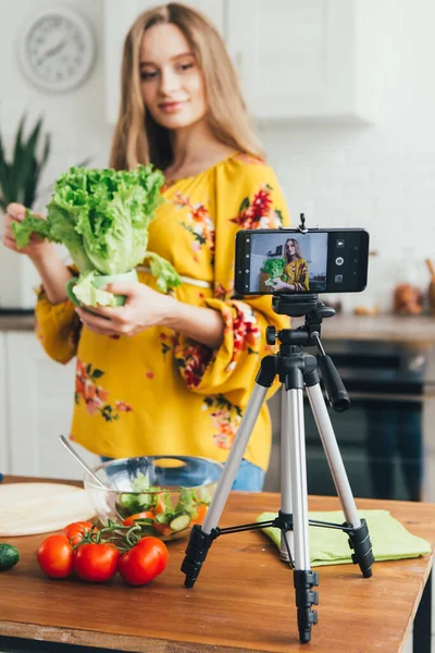 Genç, güzel, hamile kız blogcu akıllı telefon kamerasıyla salata tarifinin videosunu çekiyor. Sağlıklı beslenme kavramı. Tonlama.