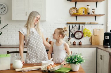 Sevimli küçük kız, annenin mutfakta kurabiye pişirmesine yardım ediyor. Mutlu bir aile. Tonlama.
