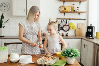 Sevimli küçük kız, annenin mutfakta kurabiye pişirmesine yardım ediyor. Mutlu bir aile. Tonlama.