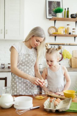 Sevimli küçük kız, annenin mutfakta kurabiye pişirmesine yardım ediyor. Mutlu bir aile. Tonlama.