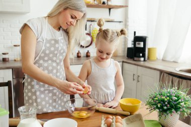 Sevimli küçük kız, annenin mutfakta kurabiye pişirmesine yardım ediyor. Mutlu bir aile. Tonlama.