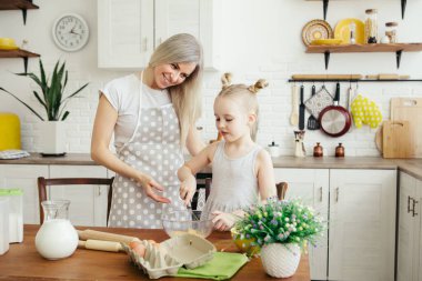 Sevimli küçük kız, annenin mutfakta kurabiye pişirmesine yardım ediyor. Mutlu bir aile. Tonlama.