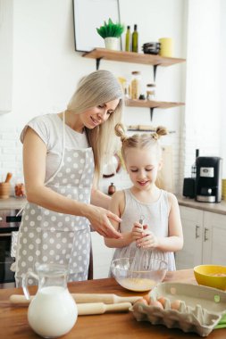 Sevimli küçük kız, annenin mutfakta kurabiye pişirmesine yardım ediyor. Mutlu bir aile. Tonlama.