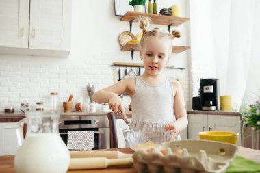 Sevimli küçük kız, annenin mutfakta kurabiye pişirmesine yardım ediyor. Mutlu bir aile. Tonlama.