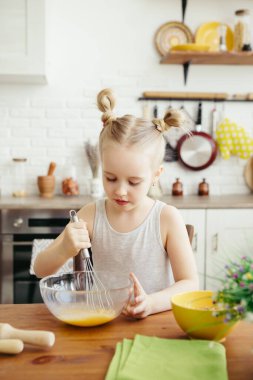 Sevimli küçük kız, annenin mutfakta kurabiye pişirmesine yardım ediyor. Mutlu bir aile. Tonlama.