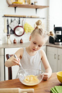 Sevimli küçük kız, annenin mutfakta kurabiye pişirmesine yardım ediyor. Mutlu bir aile. Tonlama.