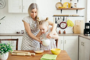 Sevimli küçük kız, annenin mutfakta kurabiye pişirmesine yardım ediyor. Mutlu bir aile. Tonlama.