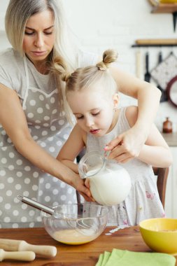 Sevimli küçük kız, annenin mutfakta kurabiye pişirmesine yardım ediyor. Mutlu bir aile. Tonlama.