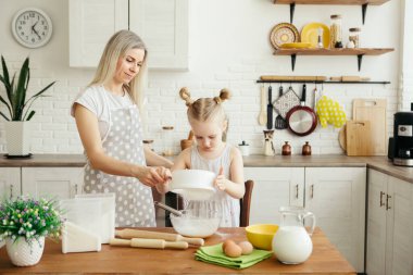 Sevimli küçük kız, annenin mutfakta kurabiye pişirmesine yardım ediyor. Mutlu bir aile. Tonlama.
