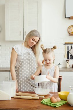 Sevimli küçük kız, annenin mutfakta kurabiye pişirmesine yardım ediyor. Mutlu bir aile. Tonlama.