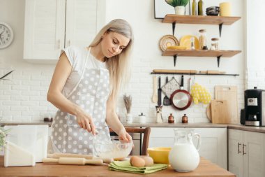 Genç ve güzel bir kadın mutfakta kurabiye pişirmek için hamur yoğurur. Tonlama.