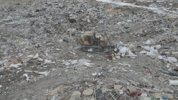 Trator bulldozer empurra lixo de uma montanha em uma lixeira da cidade — Vídeo de Stock