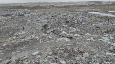 Buldozer traktörü şehir çöplüğündeki bir dağdan çöp atıyor.