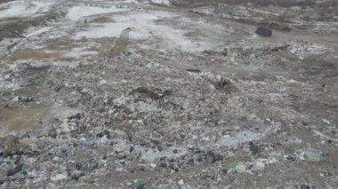 Buldozer traktörü şehir çöplüğündeki bir dağdan çöp atıyor.