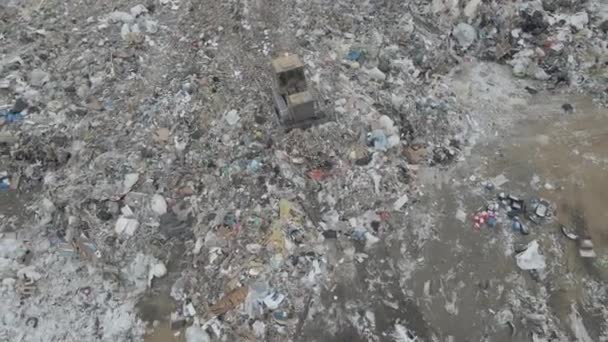 Tractor excavadora empuja la basura de una montaña en un vertedero de la ciudad — Vídeos de Stock