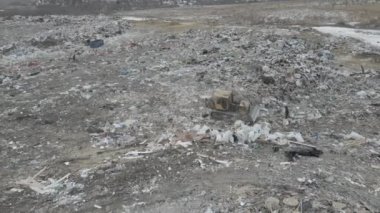 Buldozer traktörü şehir çöplüğündeki bir dağdan çöp atıyor.