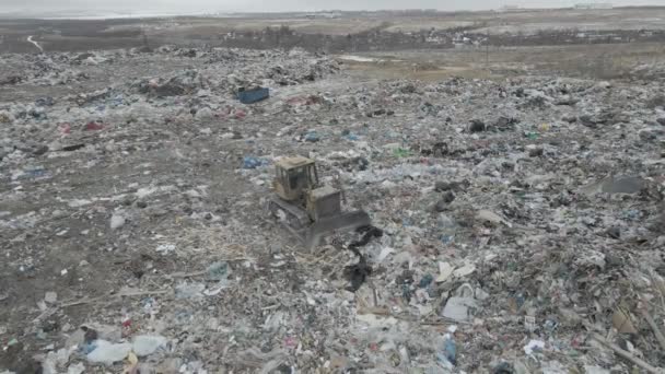 Trattore bulldozer spinge spazzatura da una montagna in una discarica della città — Video Stock