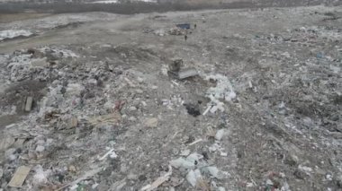 Buldozer traktörü şehir çöplüğündeki bir dağdan çöp atıyor.