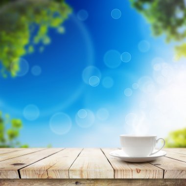 Fincan yeşil bokeh ve güneş ışığı üzerinde masada sıcak içecekle