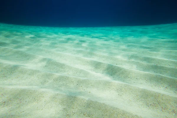 Fondo di mare sabbioso con sfondo blu acqua — Foto Stock