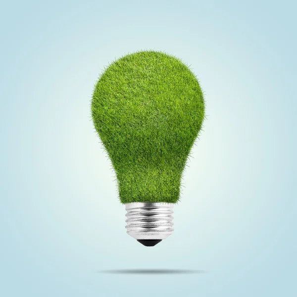 Light bulb with green grass isolated over blue background — Stock Photo, Image